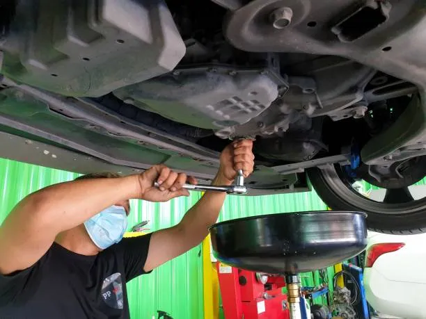 Teknisi profesional sedang melakukan penggantian oli mobil di bengkel