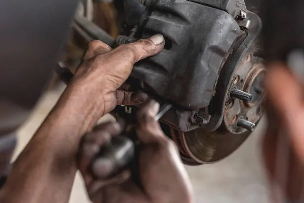 Mekanik profesional sedang melakukan perbaikan sistem rem mobil di bengkel.